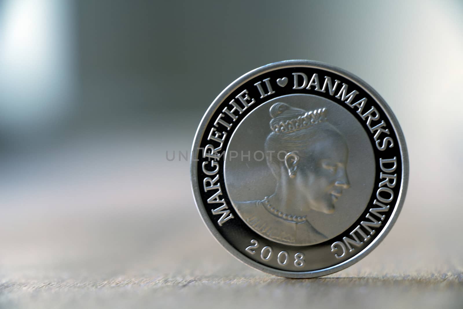 Danish silver coin with the danish queen on wooden table on a cloudy day.