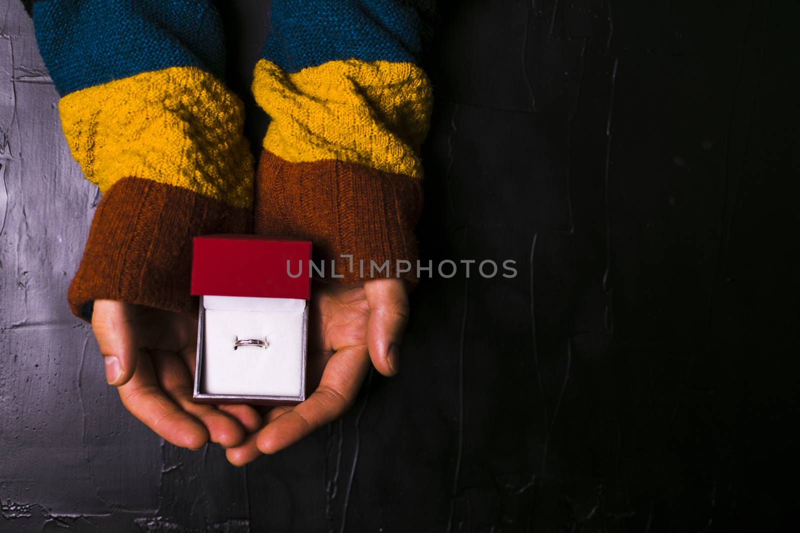 Male hand holds out a ring on a black background