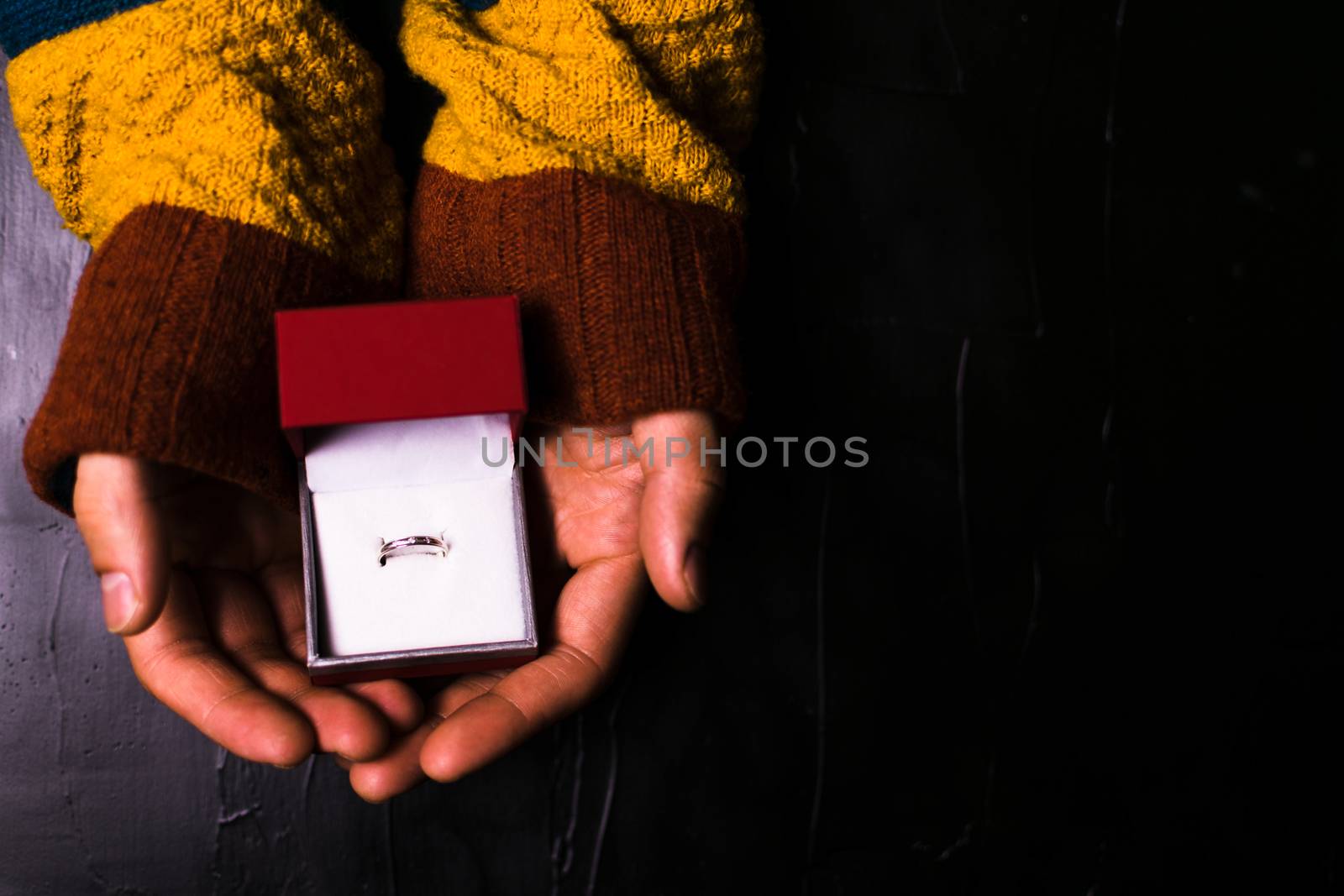 Male hand holds out a ring on a black background