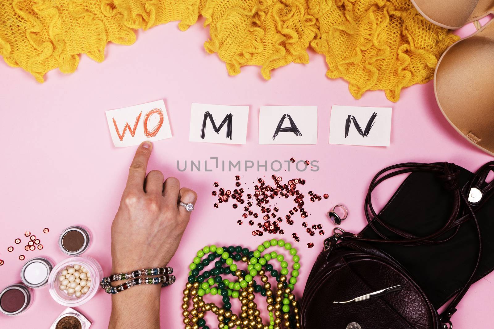 Man in women's jewelry puts the inscription on pink background