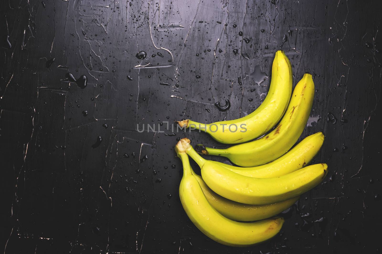 Apples and bananas on a dark background with splashes of water