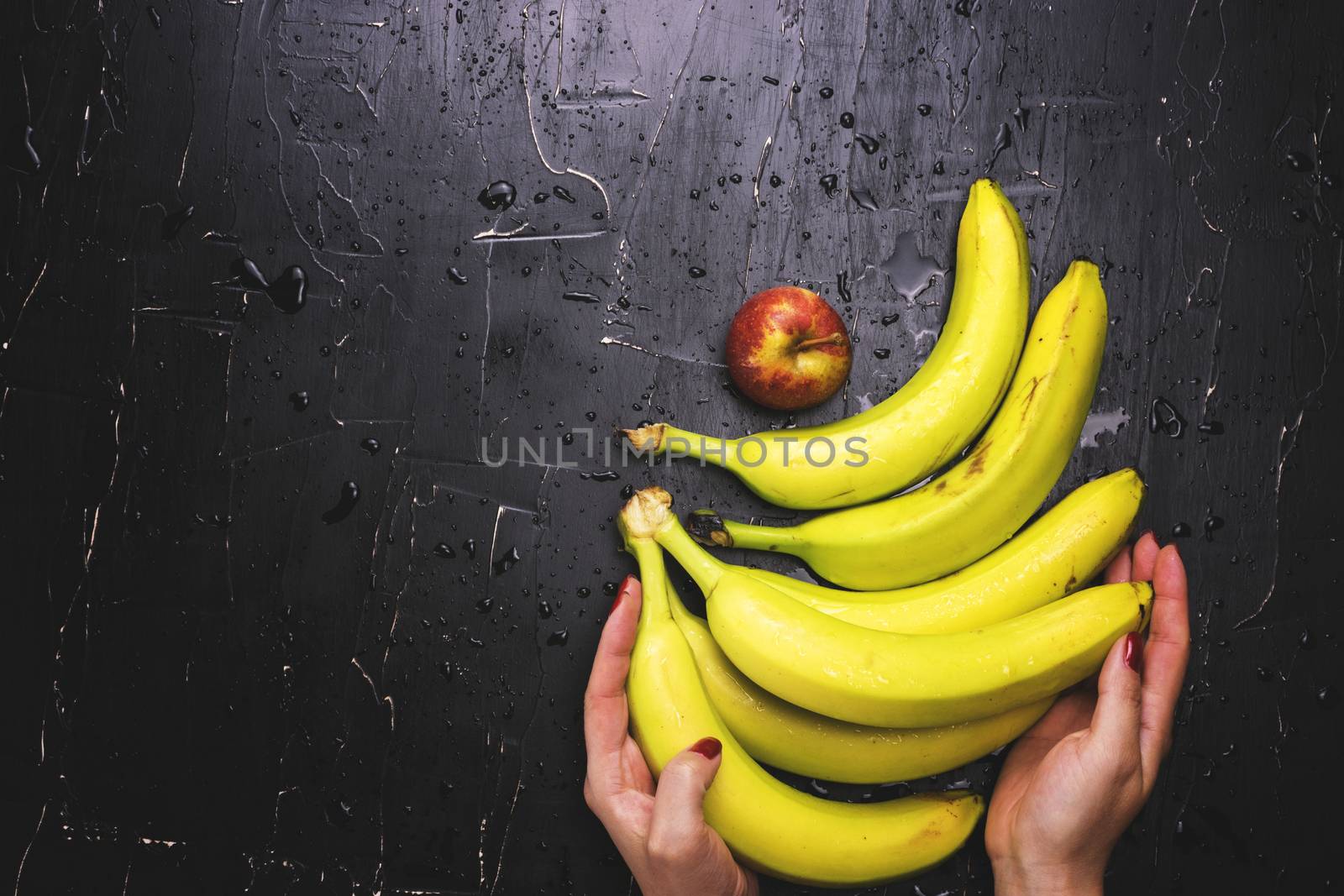 She lays out the apples and bananas on a dark background