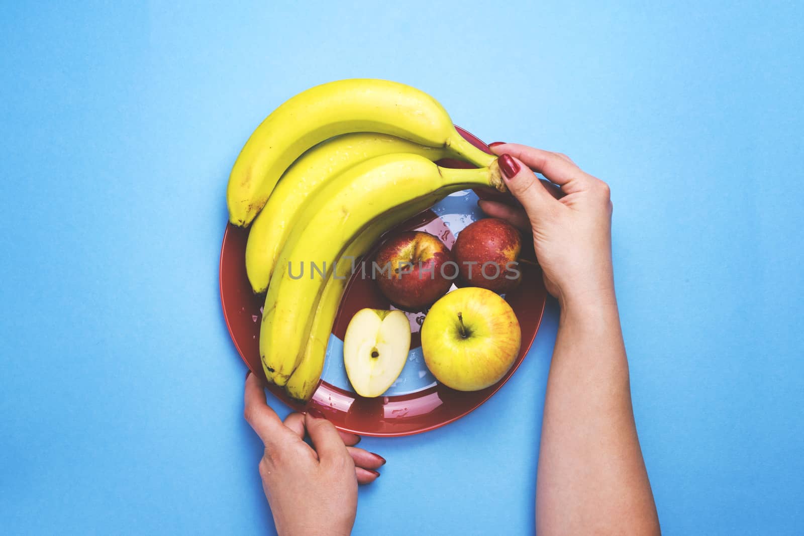 Girl holding a plate of fruit on a color background. The concept of healthy eating, diet.