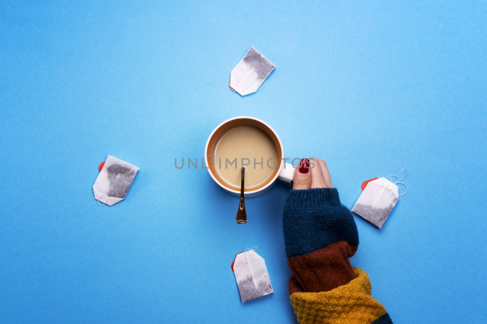 Girl holding a Cup of coffee surrounded by tea bags. The concept of beverages and preferences. Coffee pause, a break.