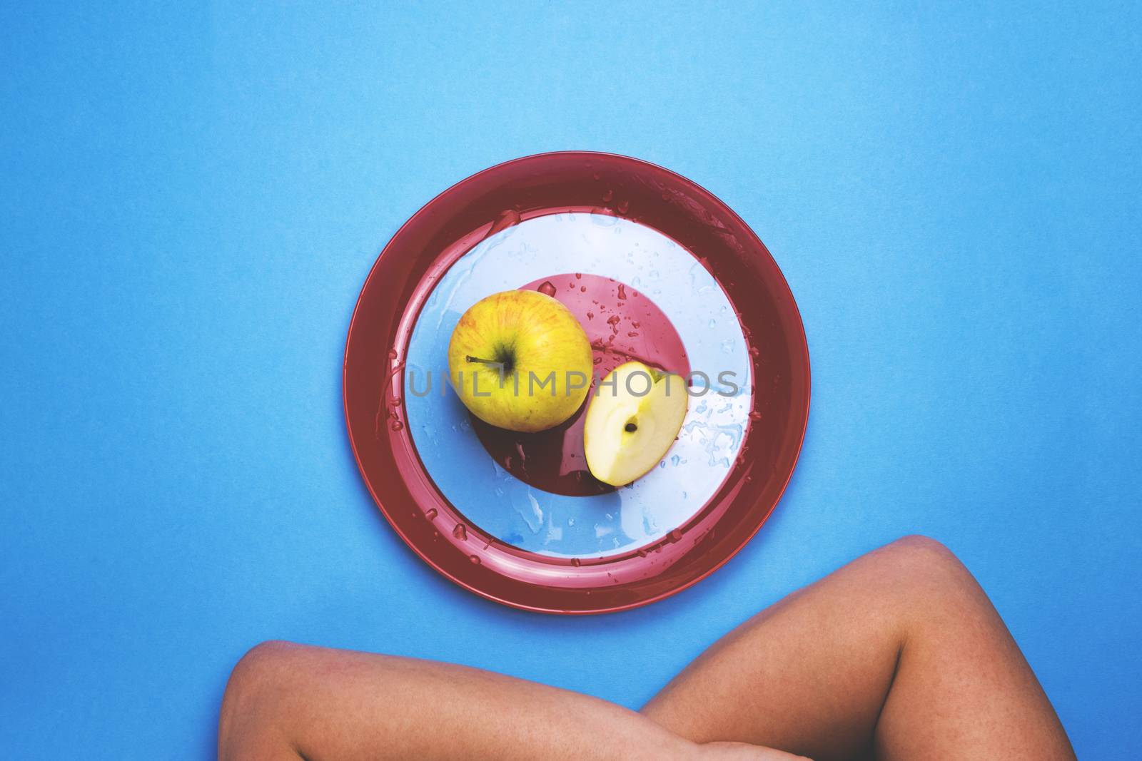 Apple on a red plate on a colored background