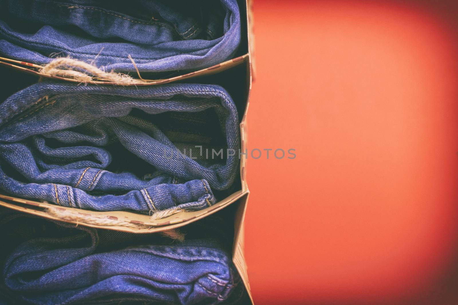 Women's jeans folded in a pile on a colored background. Made in a vintage performance.