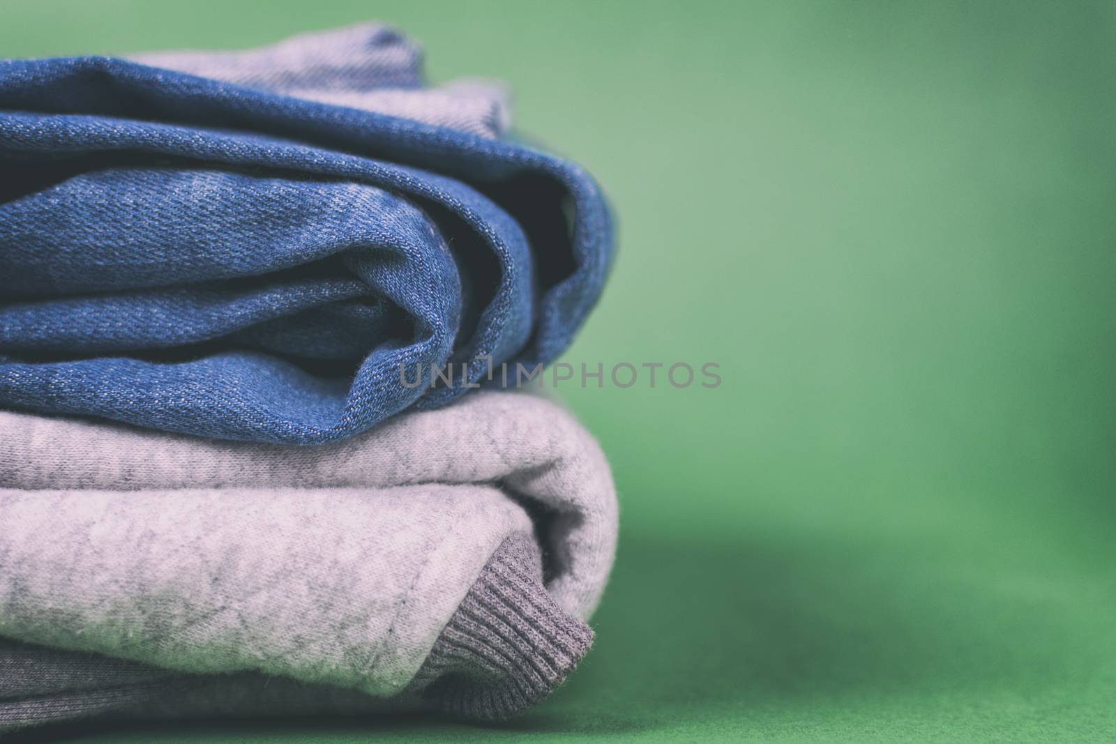 Warm and fashionable women's denim clothing folded on a colored background.