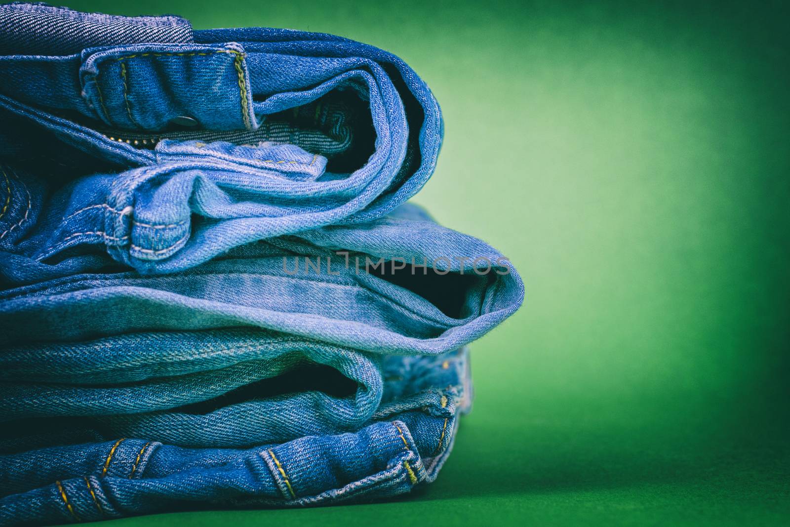Women's jeans folded in a pile on a colored background. Made in a vintage performance.
