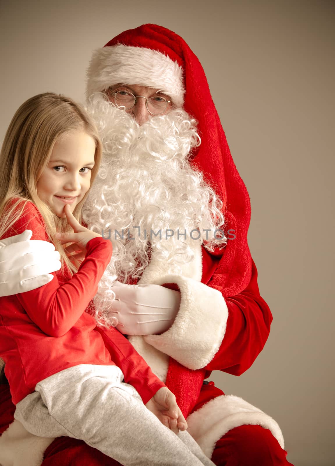 Portrait of smiling little girl sitting on santa claus knees