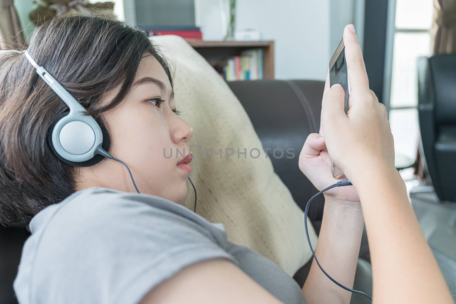 Close up young asian woman short hair listening music on the couch at home