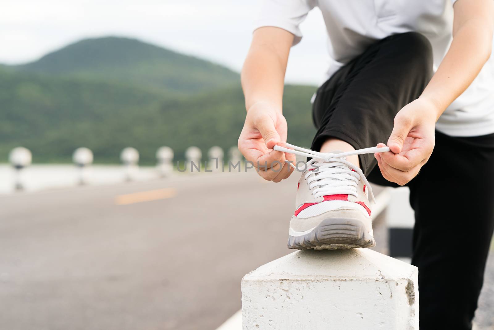 Woman tying shoelace his before starting running by stoonn