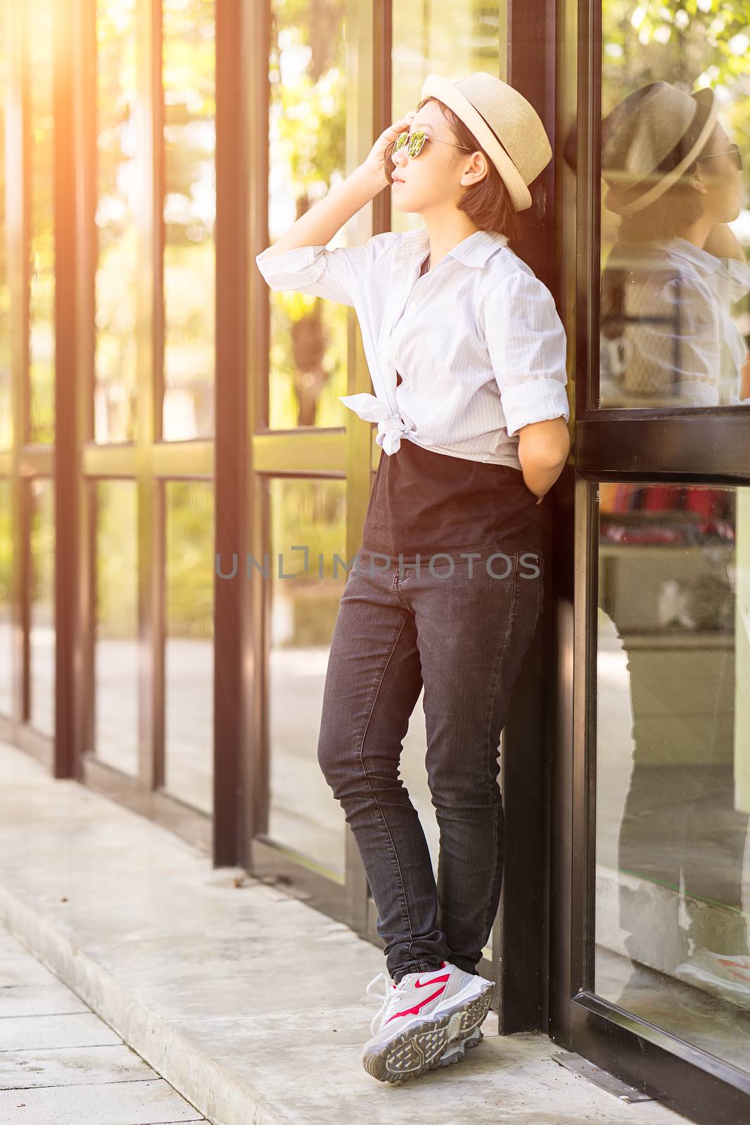 Women wearing hat standing in front of a glass building by stoonn