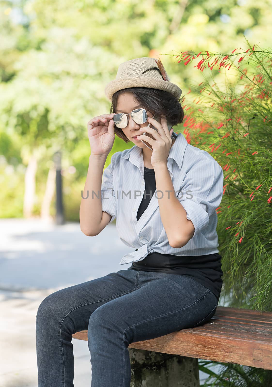 Beautiful and young women with short hair wearing hat use mobile phone in garden