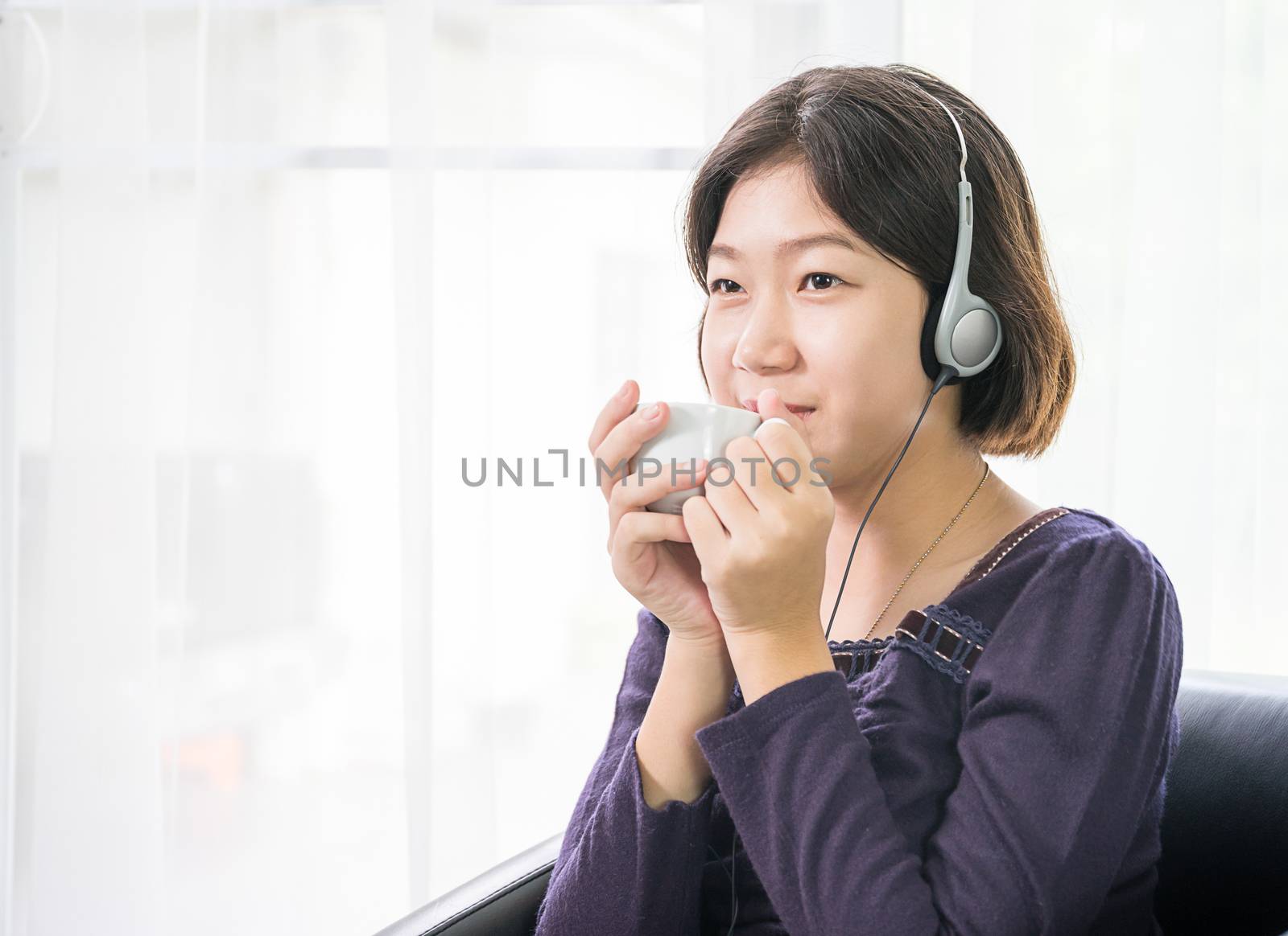 Young asian woman short hair listening music in living room by stoonn