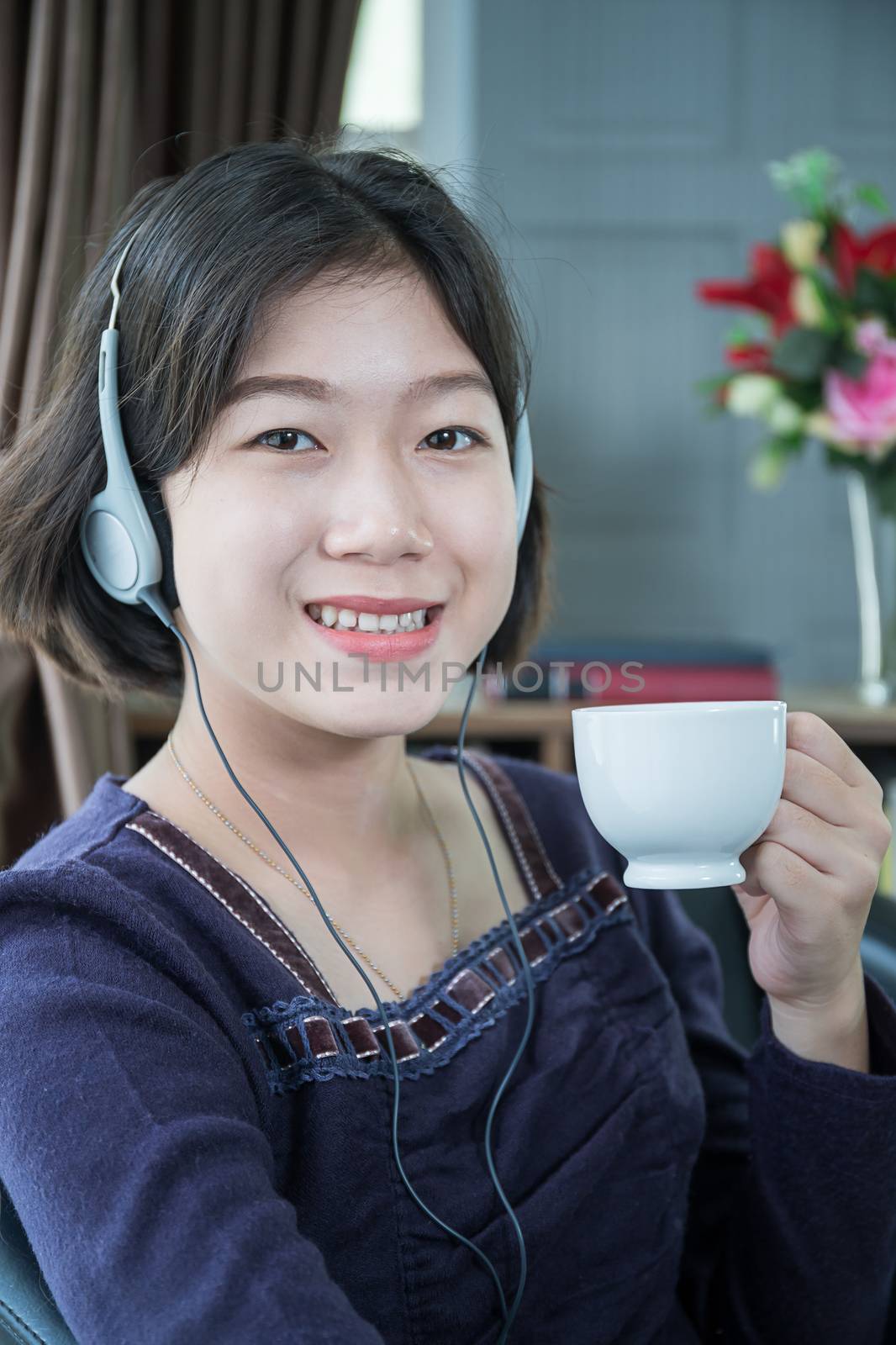 Close up beautiful young asian woman short hair listening music in living room at home