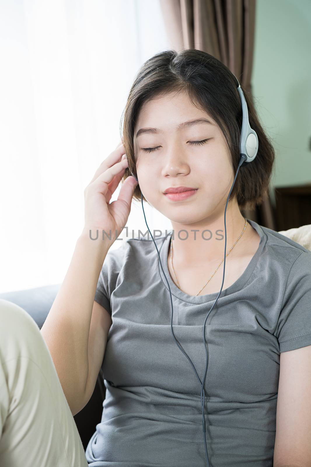 Close up young asian woman short hair listening music from mobile phone on the couch