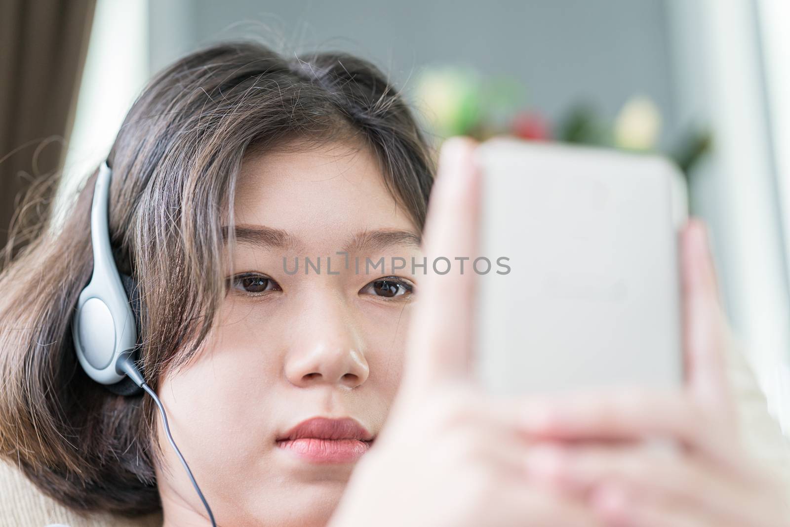 Close up young asian woman short hair listening music from mobile phone on the couch