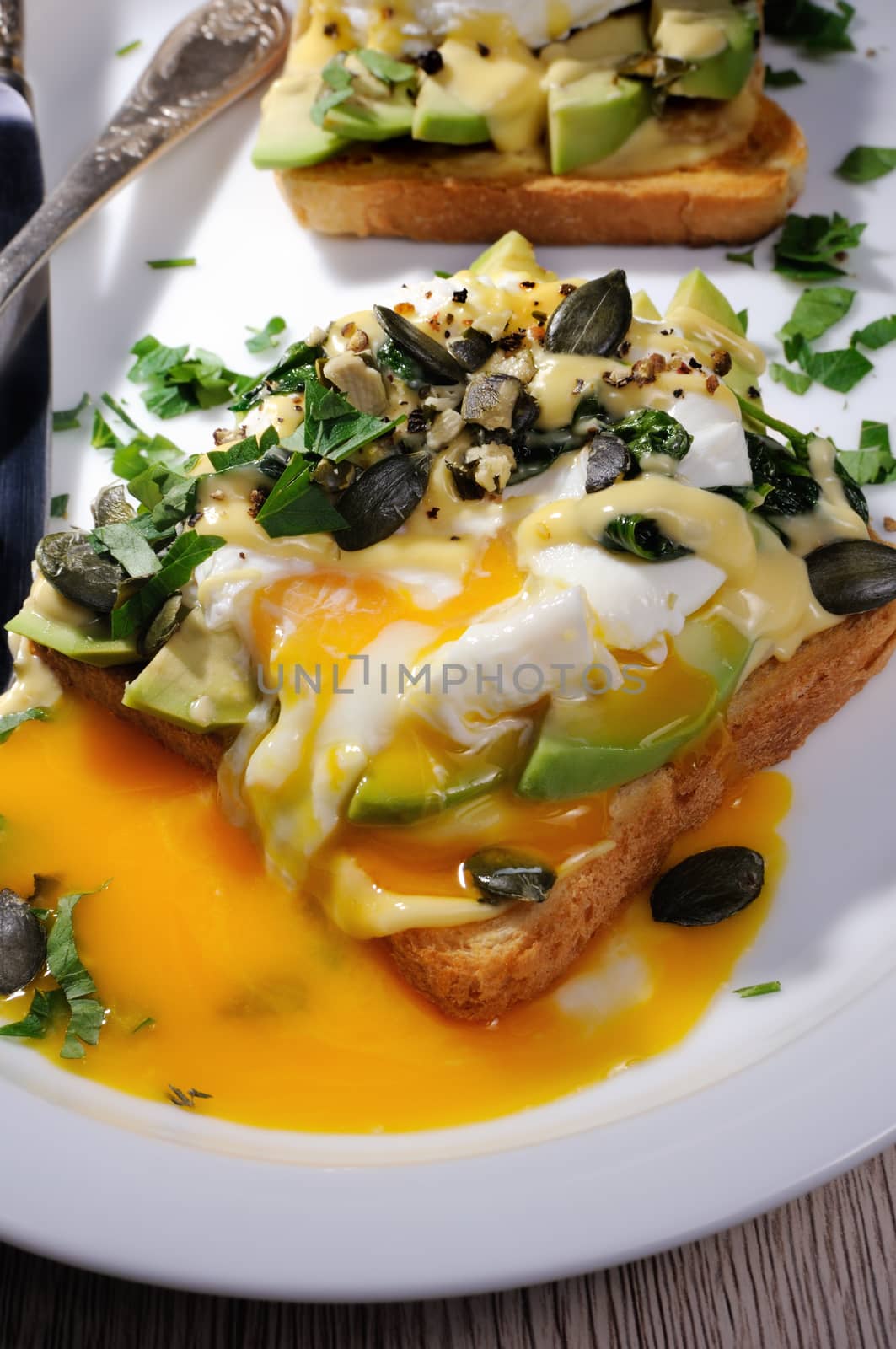 Eggs Benedict on toast with Dutch sauce, slices of avocado