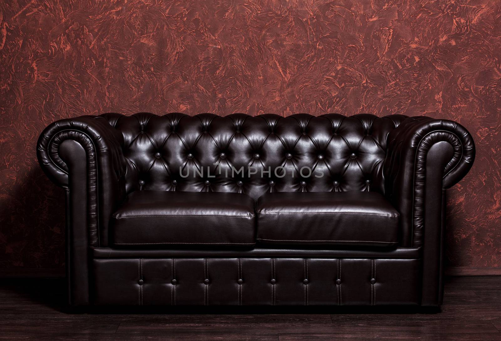 Vintage old dark brown leather sofa with grunge brown wall in the living room