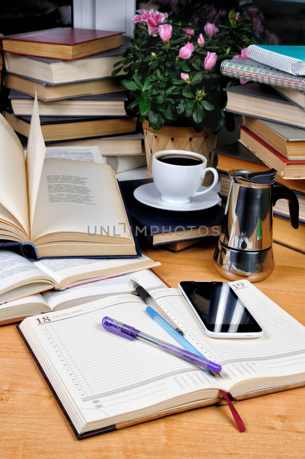 Textbooks, notepad and pen with a cup of black coffee with a coffee pot on a wooden table. Education concept.