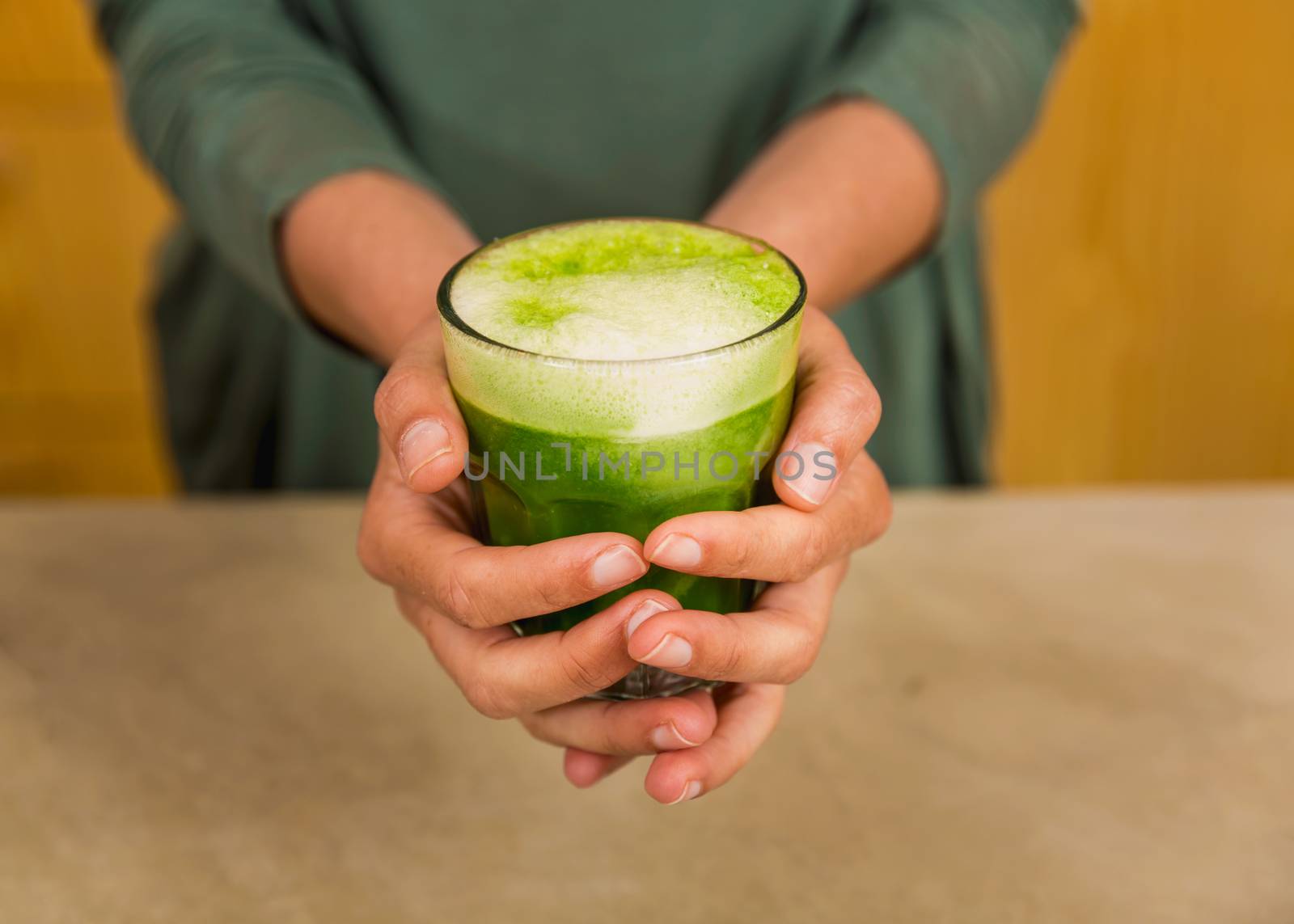 Woman holding a glass of green juice. Preparing a detox juice. 