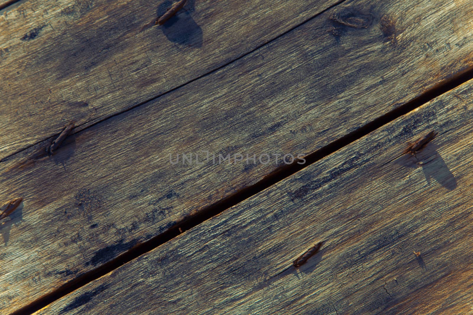 Old wooden floor with rusted nail attached to the wood surface.