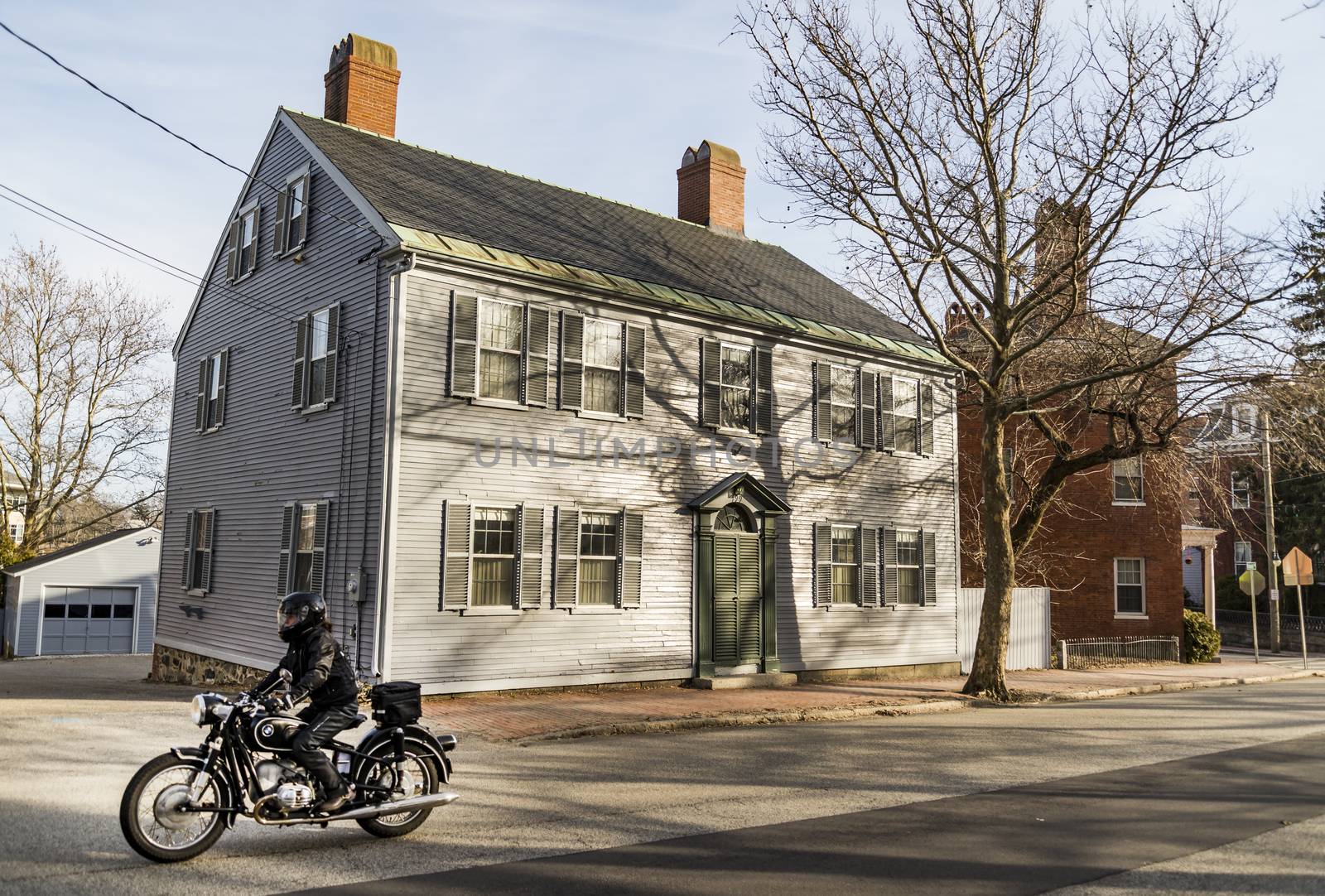 PORTSMOUTH, NH - FEBRUARY 28: Portsmouth, a city in Rockingham County, New Hampshire, is a popular summer destination. Old house with a motorbiker on the street on February 28, 2016