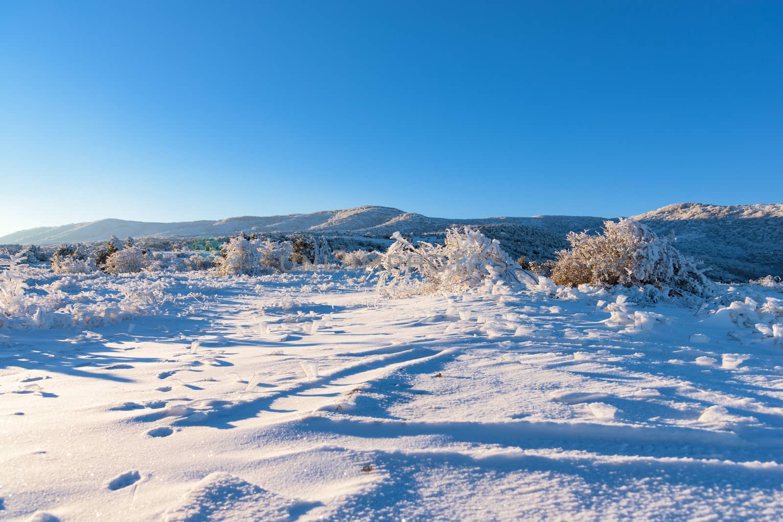 Winter amazing sunset shines on snow covered field with mountain