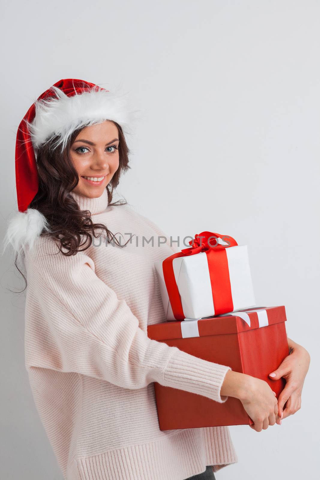 Happy woman in Santa hat with stack of Christmas gifts