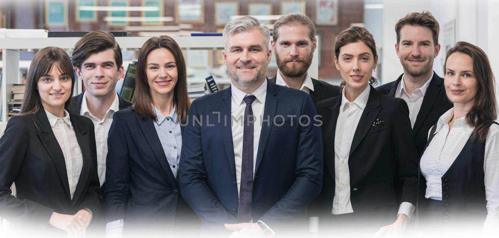 Group of friendly businesspeople with male mature leader in office