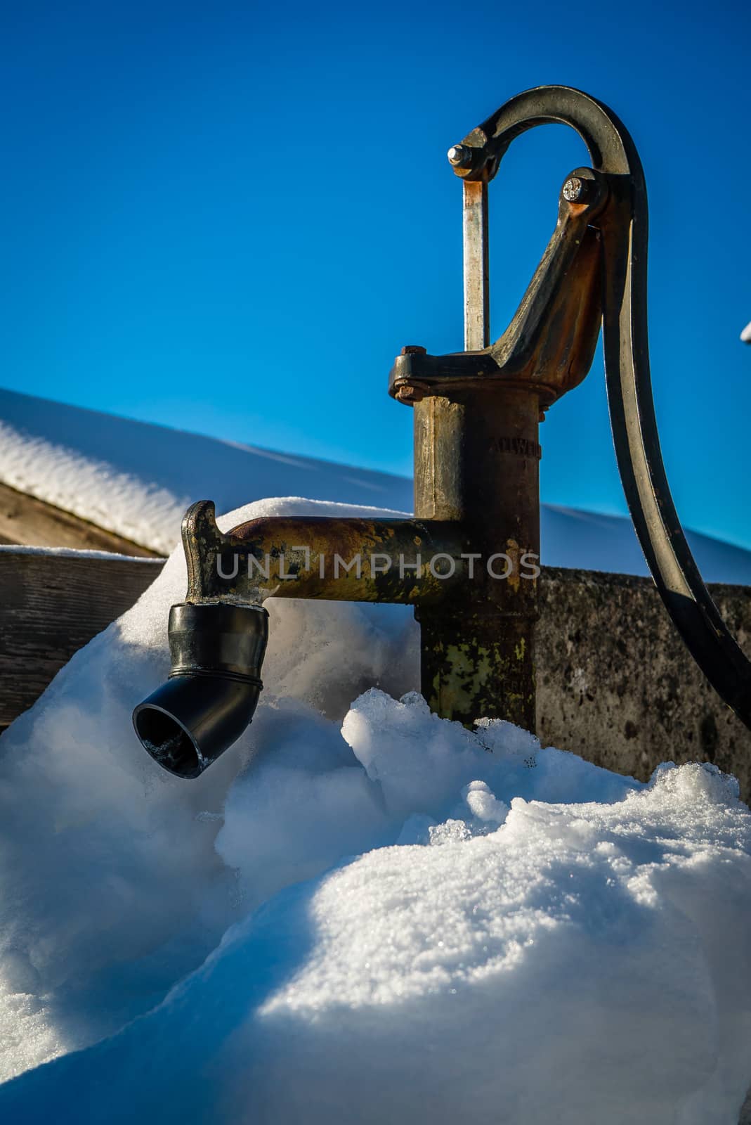 Fountain pump under the snow with a bright blue sky in winter