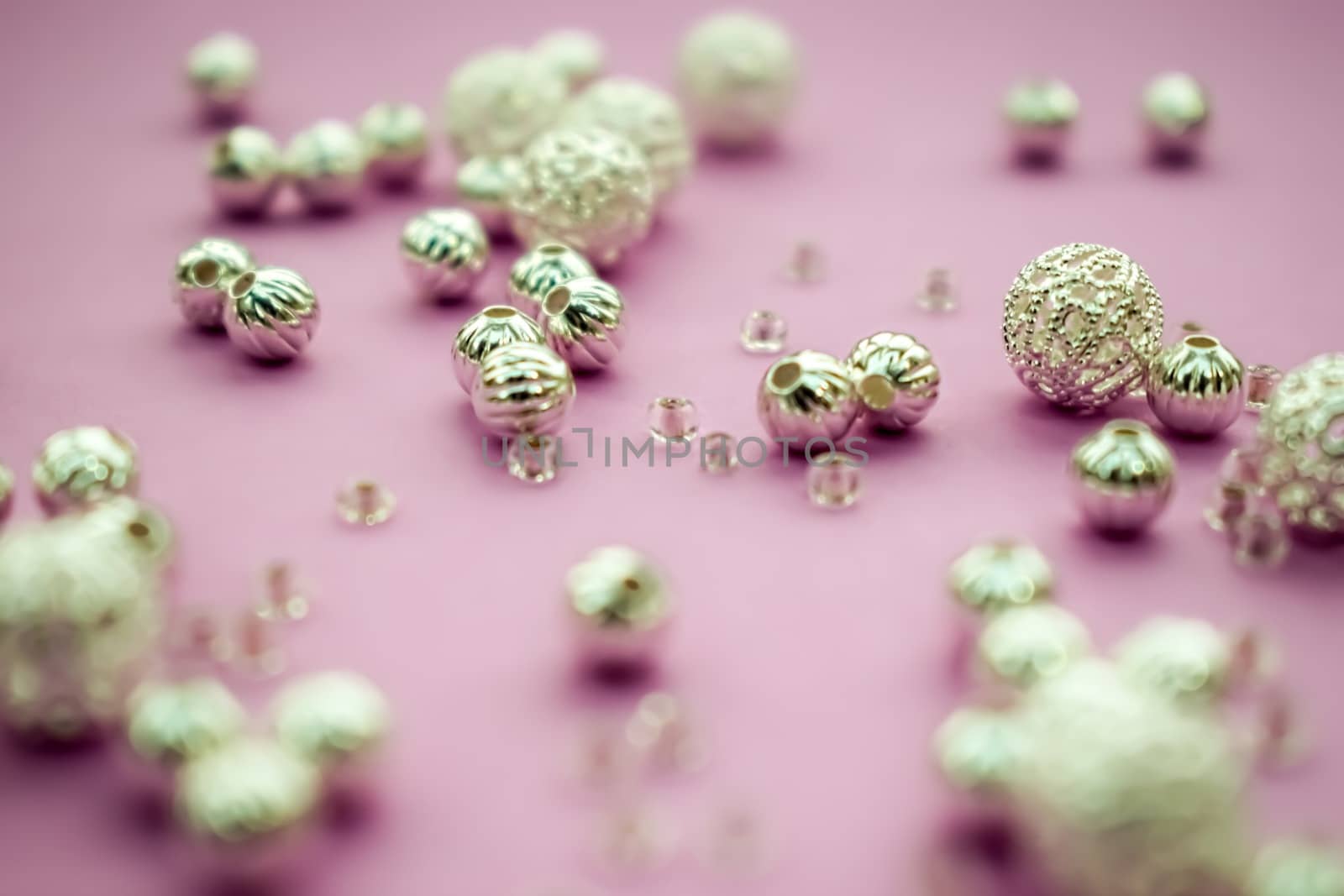 selection of scattered silver beads on pink background