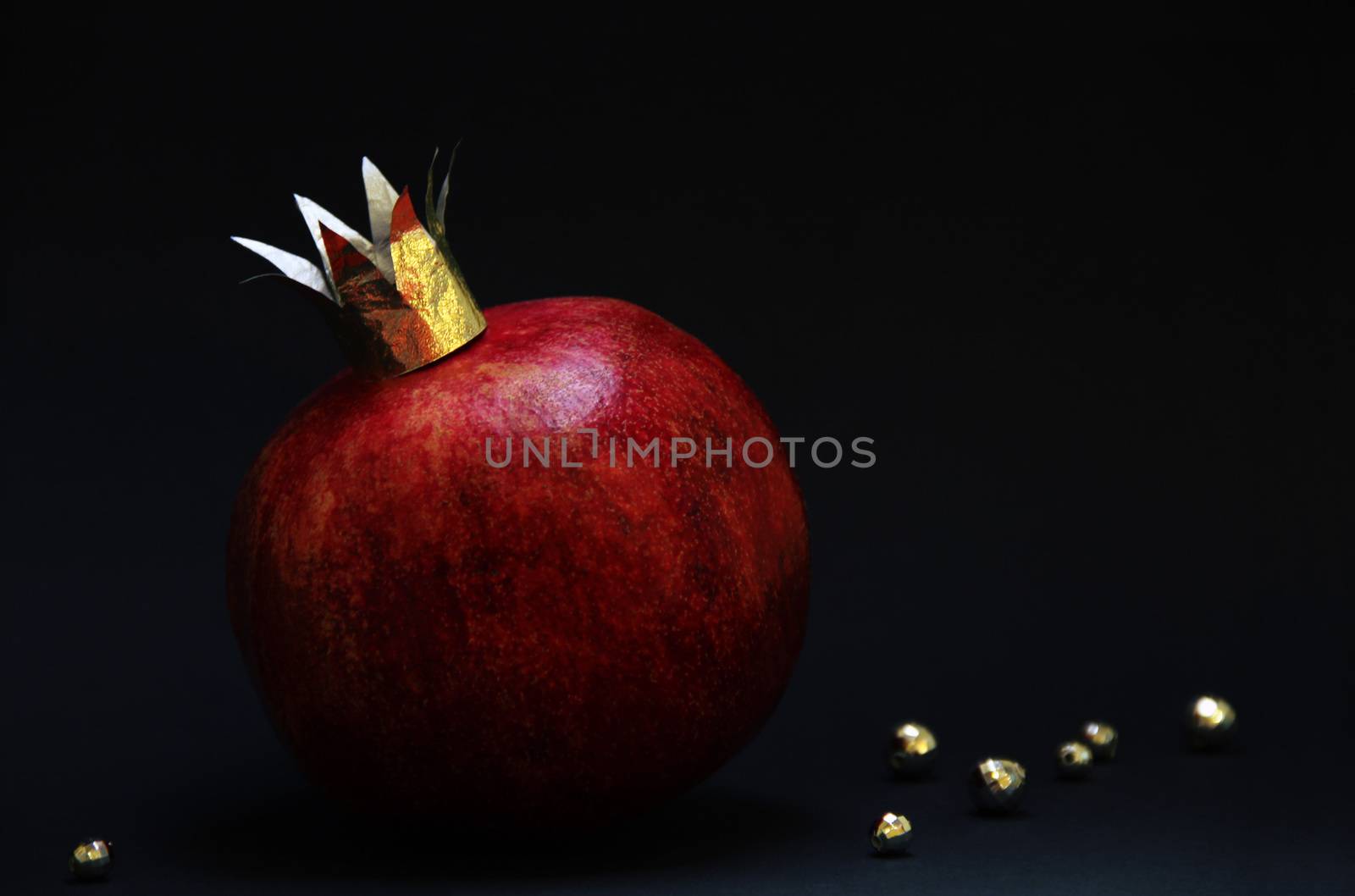 large red pomegranatre or garnet with a golden crown on a dark background. photo