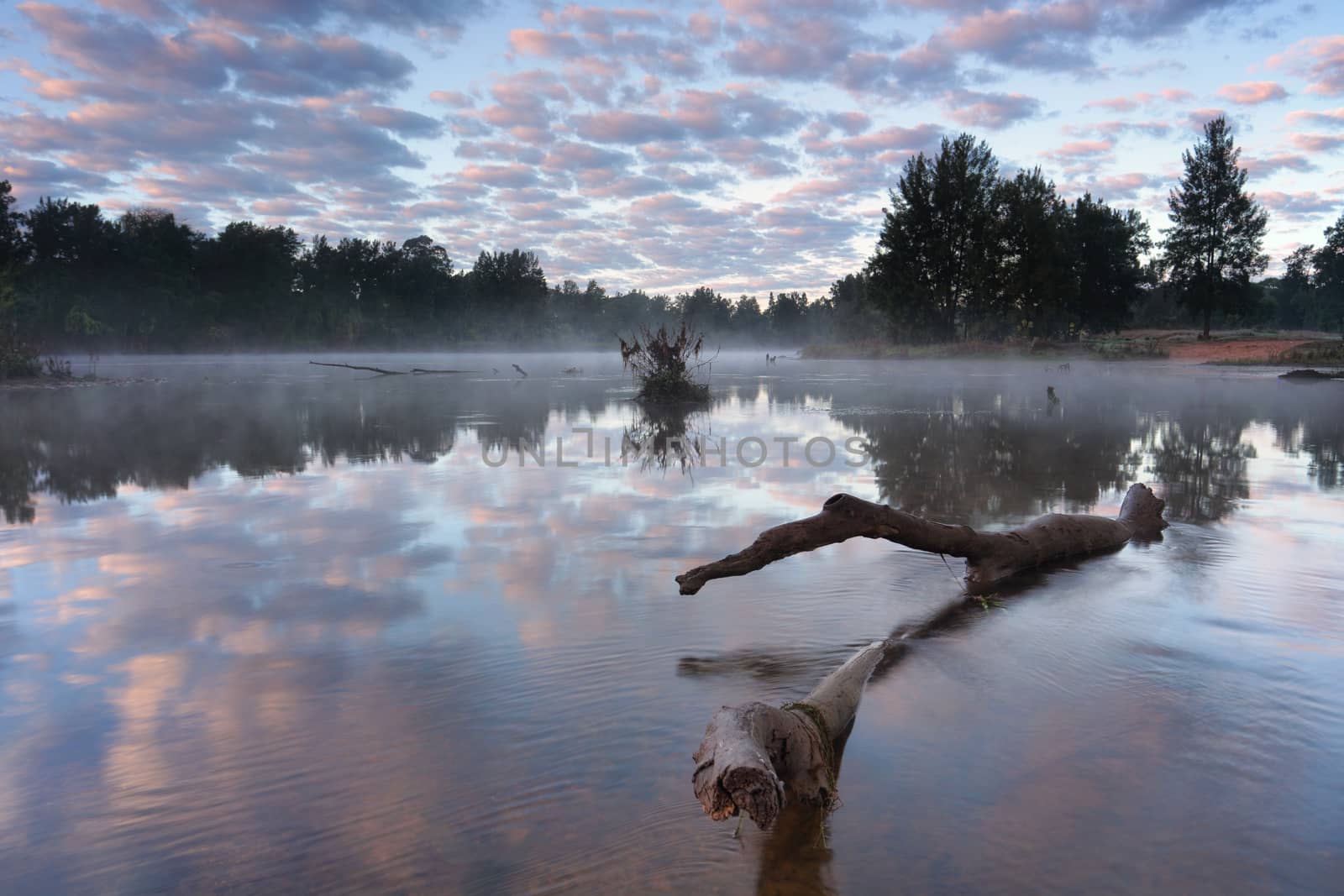Mist lightly floating above the waters surface reflecting the sky above.