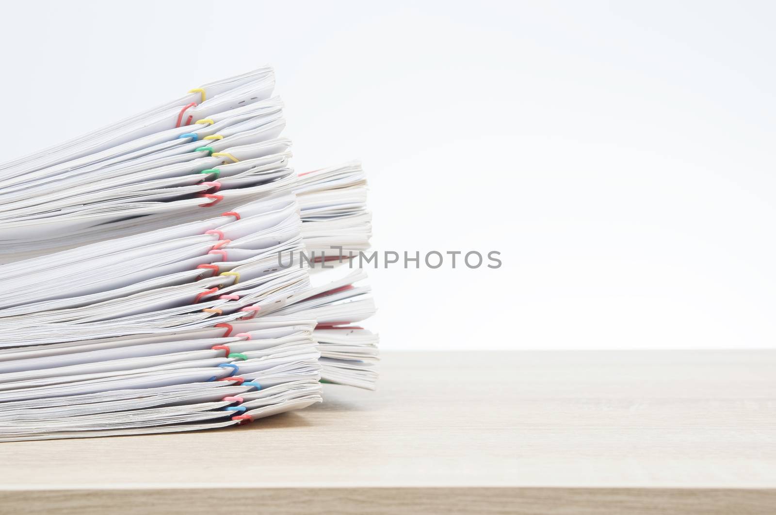 Overload paperwork report of sale and receipt with colorful paper clip on wooden table with white background and copy space. Stack document is high as work hard. Business and finance concept success.