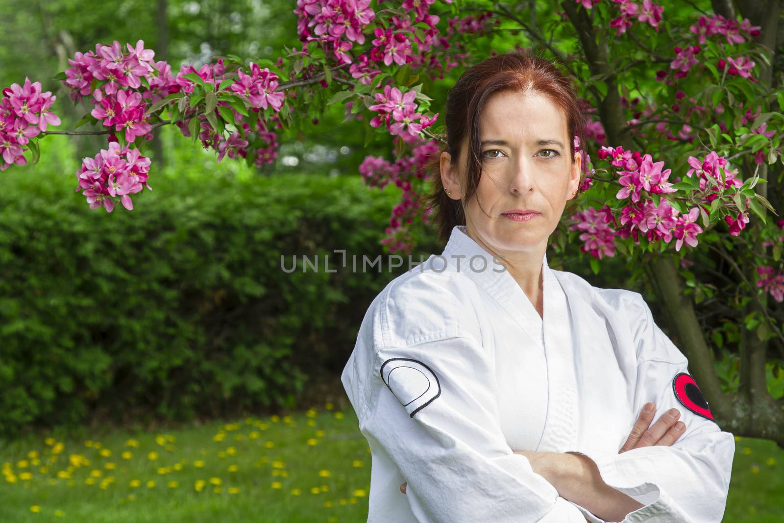 forty something martial artist woman with serious glare, under a cherry tree