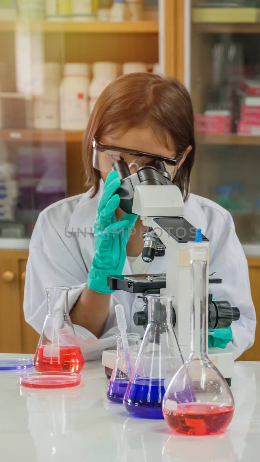 asian little scientist looking through a microscope in a laboratory