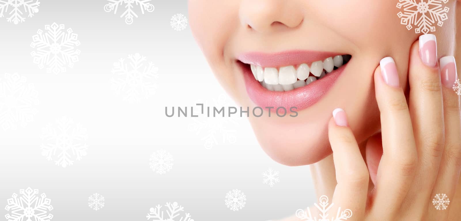 Closeup shot of woman's toothy smile against a grey background with snowflakes