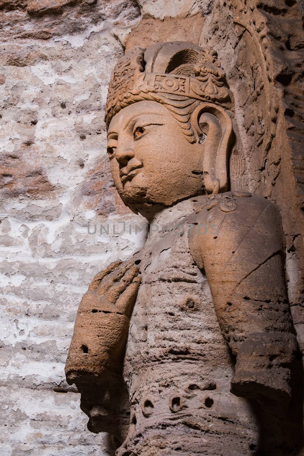Giant reddish brown stone Buddha scultpure in one of the main caves at the Yungang Grottos.