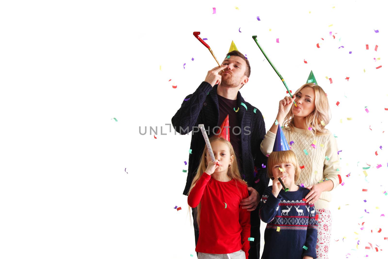 Family blowing party trumpets with confetti celebrating new year