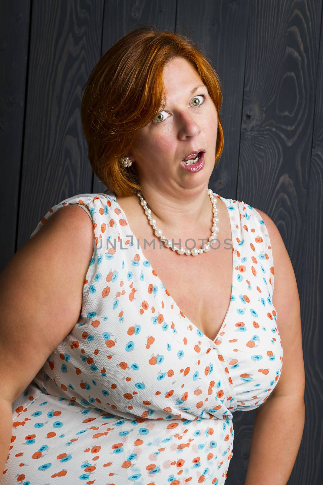 woman in her forties, in front of a blue stain wood background, with a questionning expression