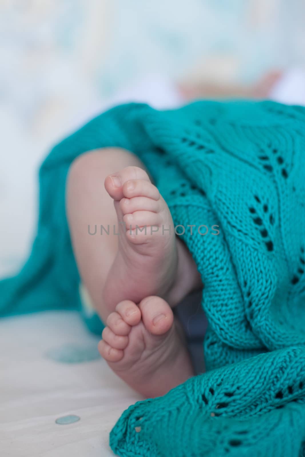 Babies cute small heels feet over the turquoise knitted blanket. Selective focus. by Katia1504