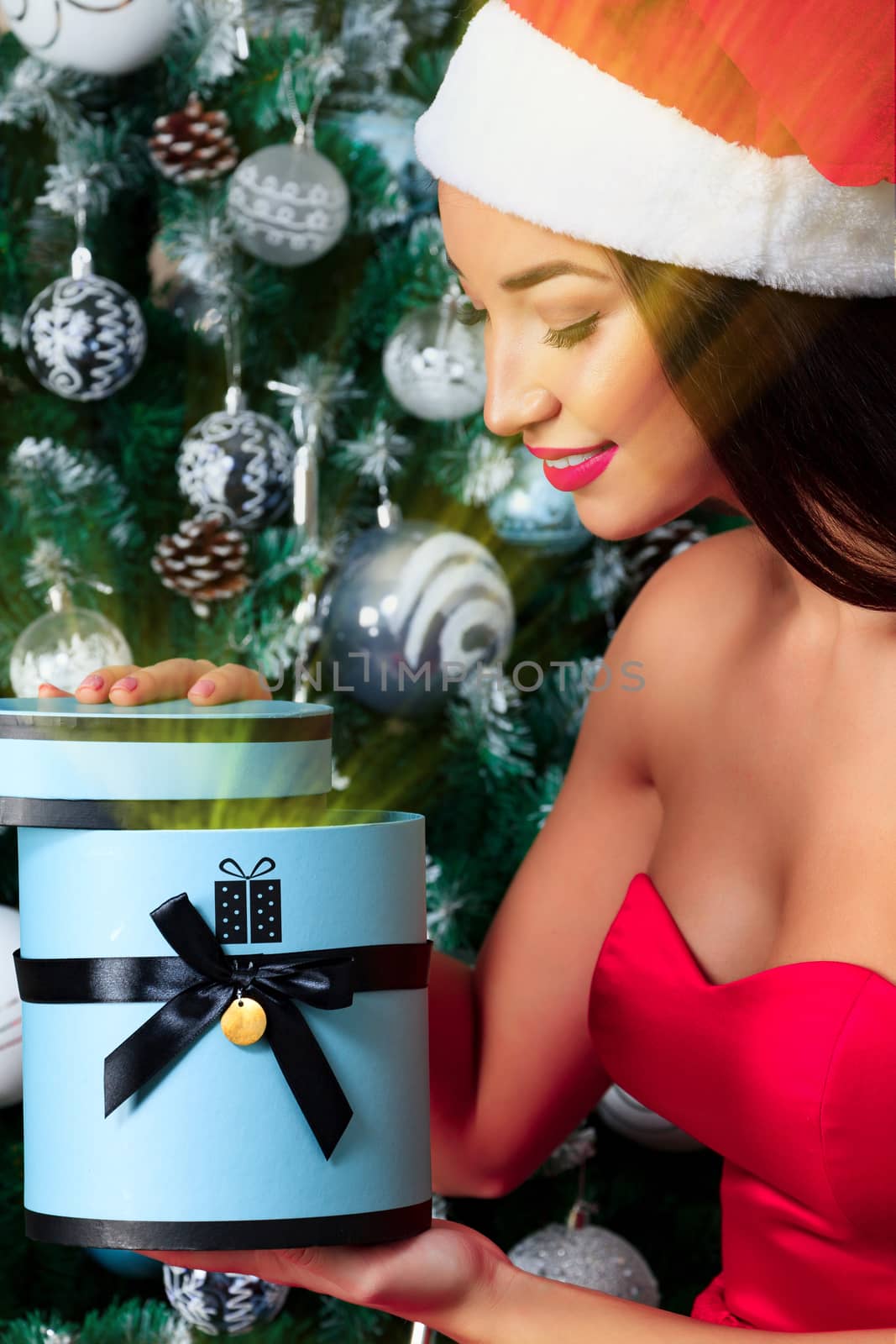 Closeup shot of young woman in red dress and hat who opens big gift box