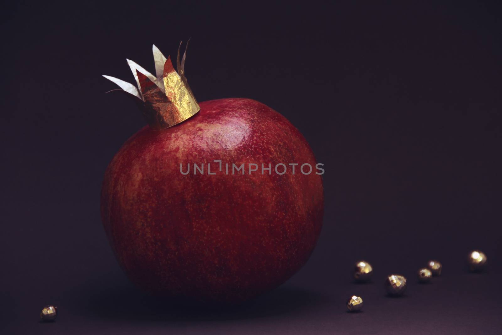 large red pomegranatre or garnet with a golden crown on a violet background. photo