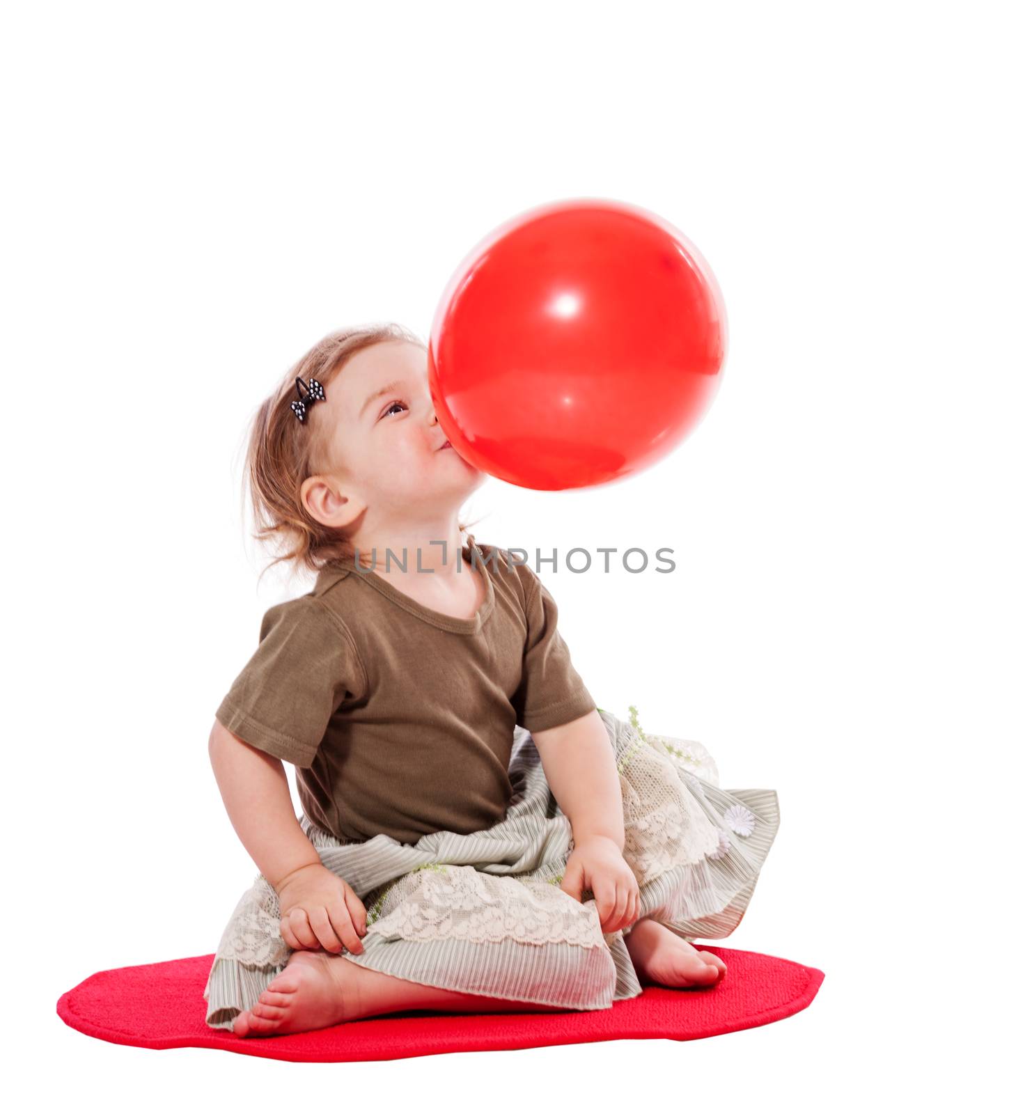 Baby holding balloon sitting on floor isolated on white