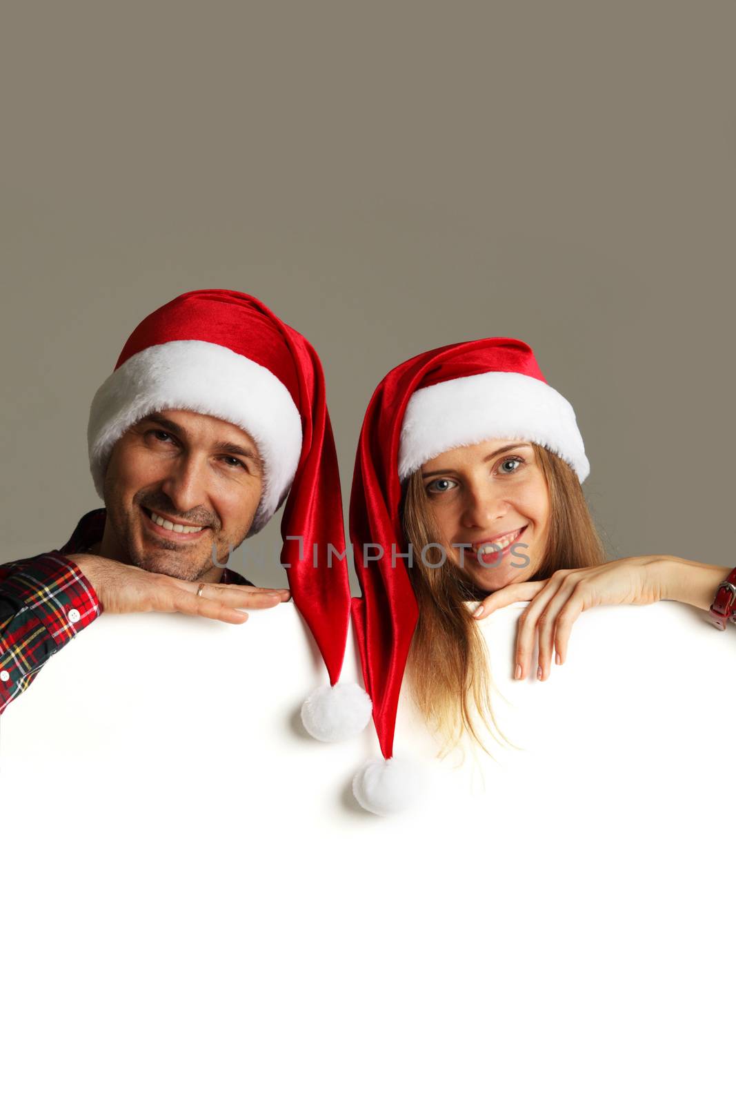 Happy couple in Santa hats holding blank banner with white copy space