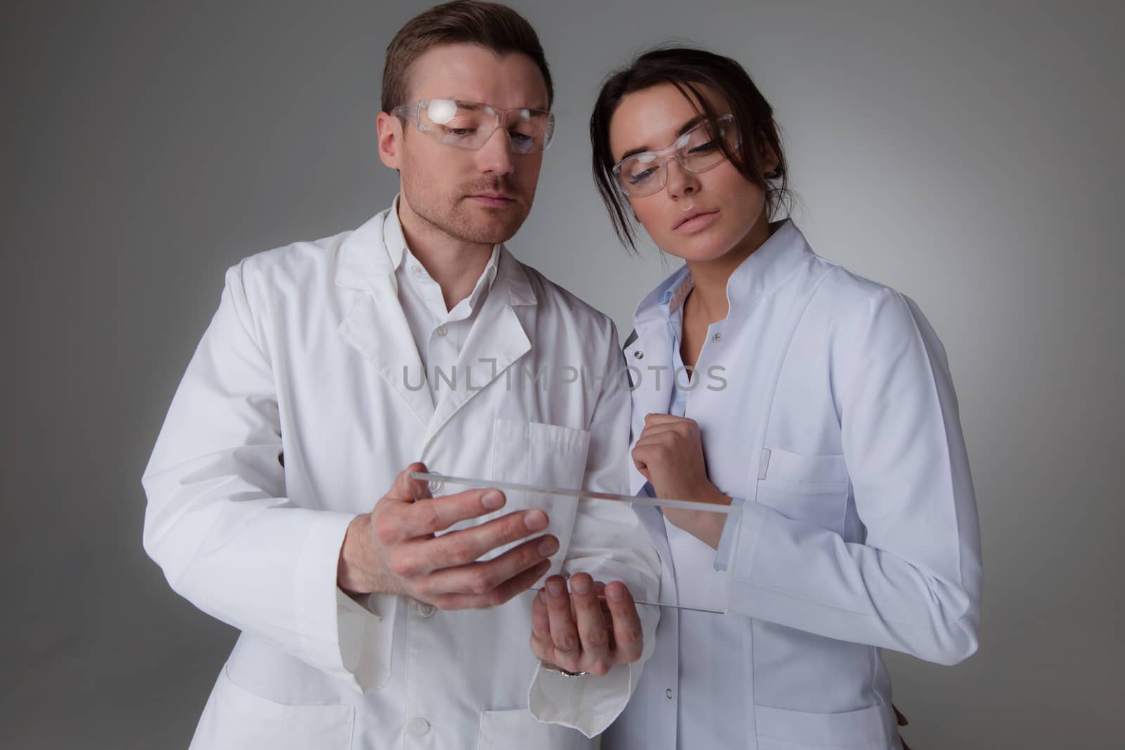 Two scientists or doctors holding blank futuristic transparent digital tablet pc computer with copy space