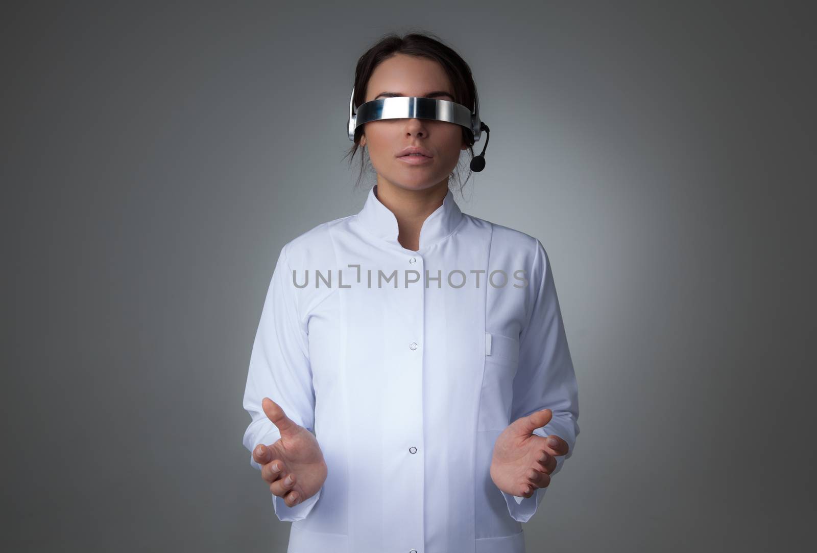 Female scientist or doctor using futuristic VR goggles headset with microphone and holding virtual object