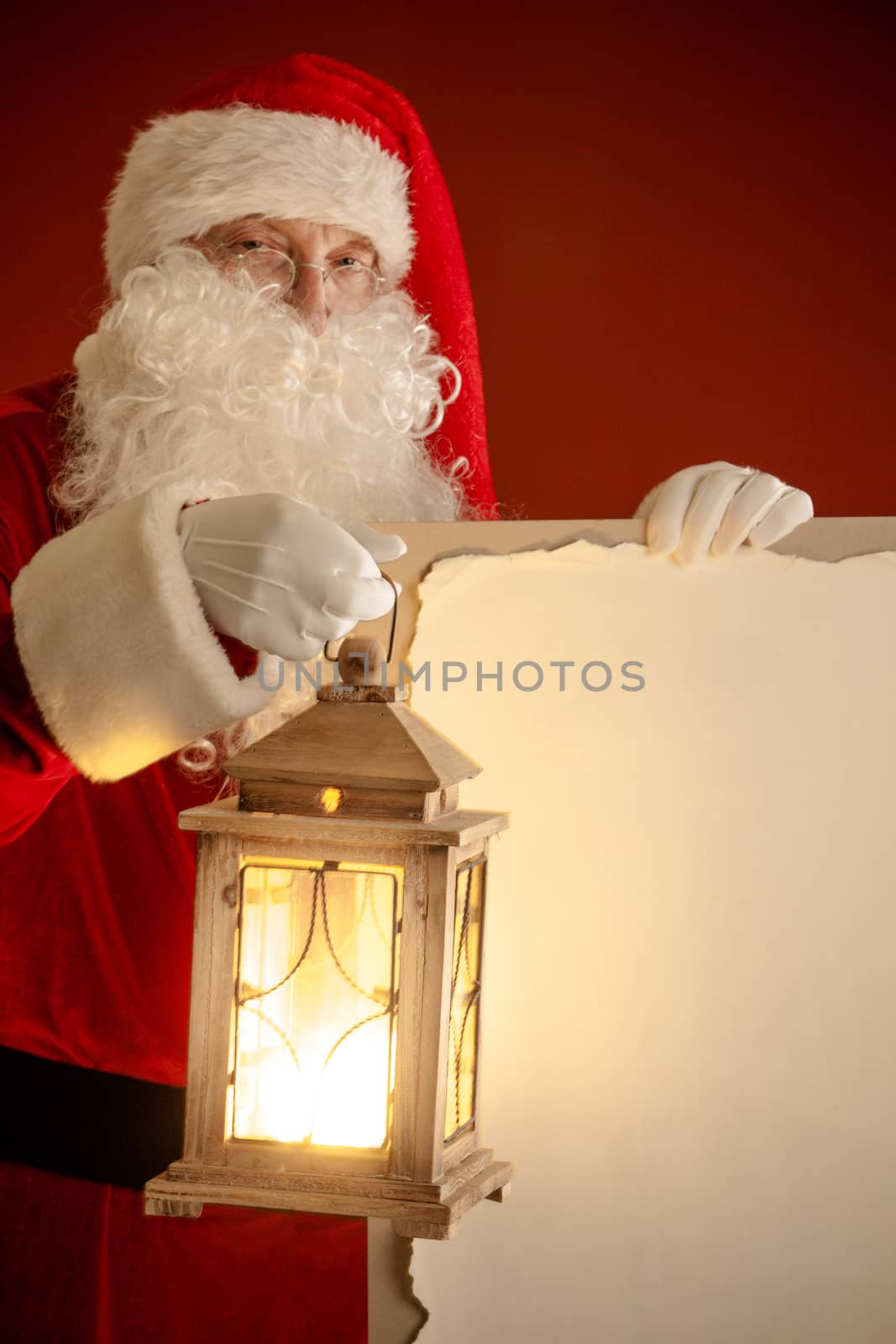 Santa Claus with lantern holding vintage paper billboard with copy space for text