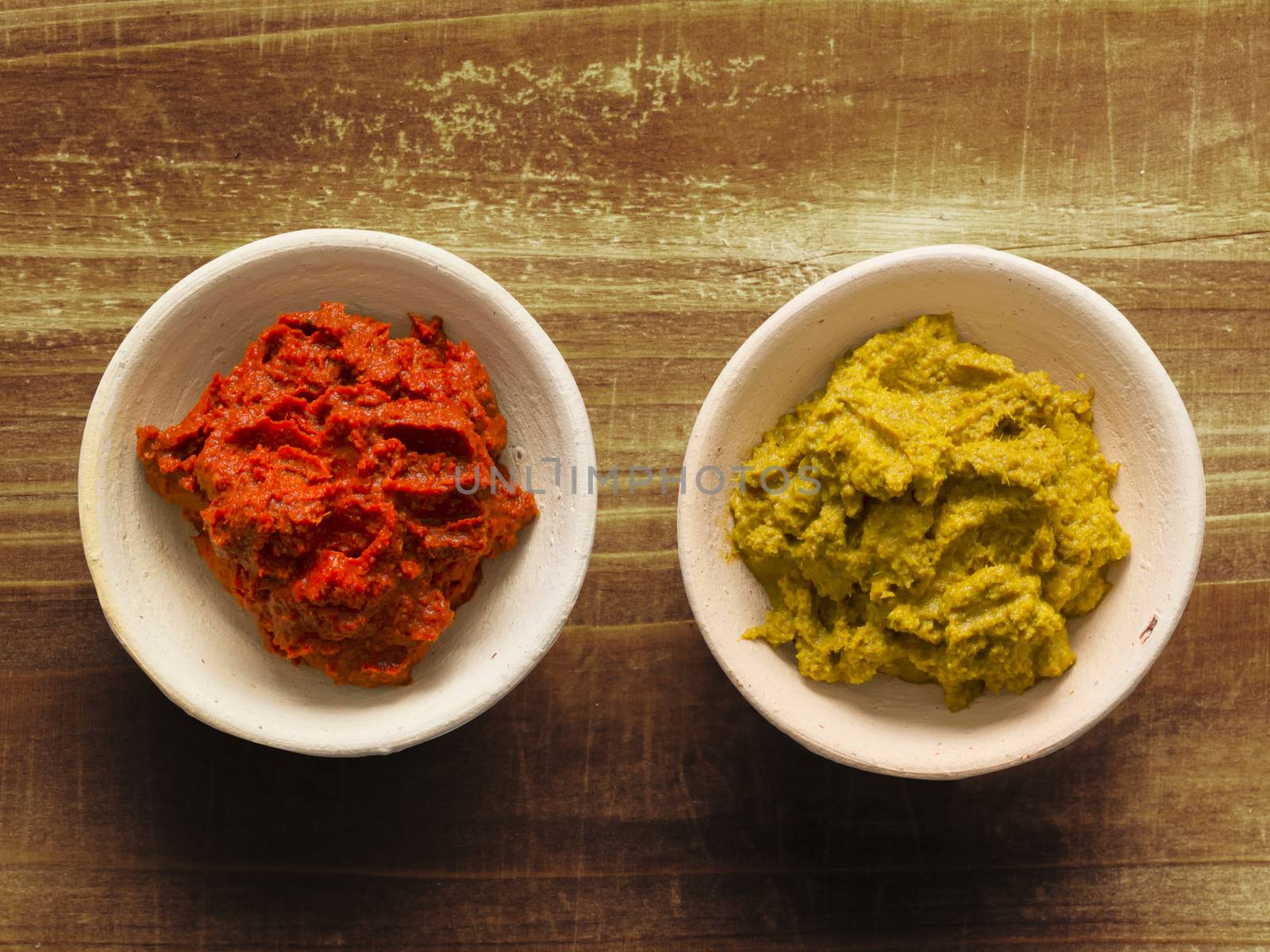 close up of bowls of rustic red and yellow indian curry paste